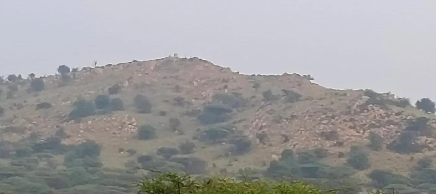 Kunnathur Hill seen from a distance, hazy, with a small built shape on its crest.